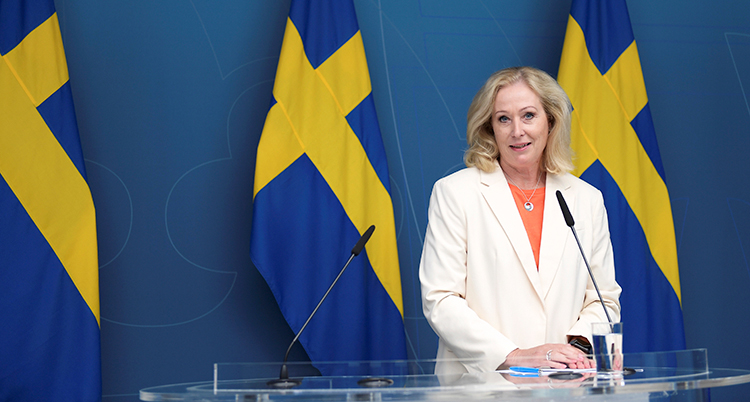 En kvinna står framför ett antal svenska flaggor.