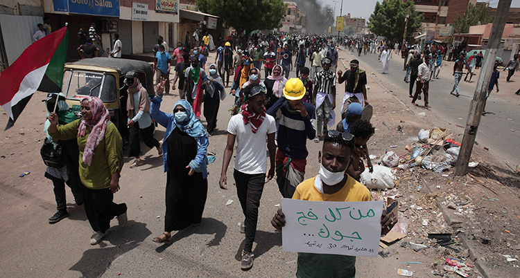 Demonstranter med plakat går på en gata i Sudan, Afrika.