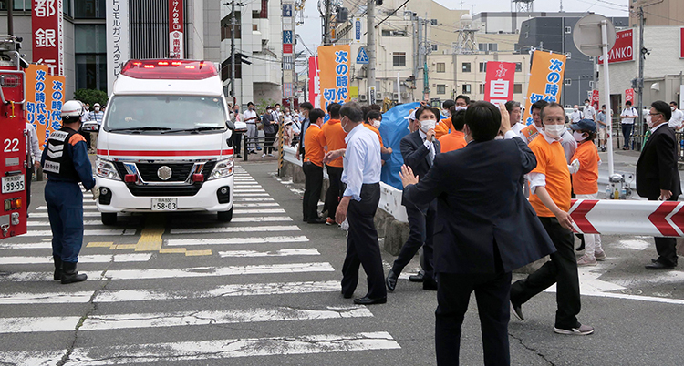En ambulans på en gata. Folk är på väg därifrån.