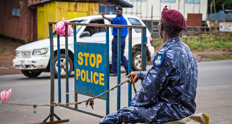 En polis i blå uniform sitter vid ett staket.
