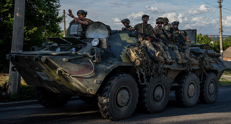 Soldater sitte ri en stridsvagn som rullar på en gata