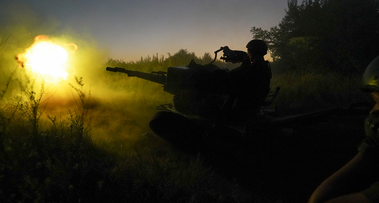 En ukrainsk soldat sitter i en tank. Det är mörkt. Men bilden lyses upp av ett skott från tanken.