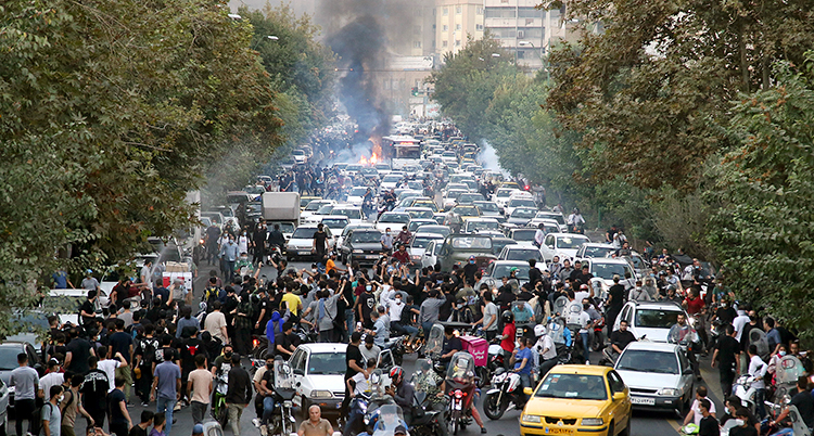 Massor av bilar och människor trängs på en bred gata.