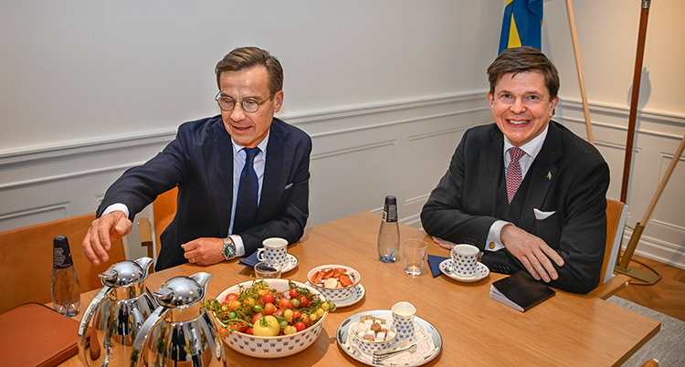 Kristersson och Norlén vid ett bord med kaffe och frukt.