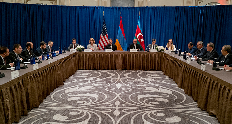 Flera människor sitter vid ett bord. Ländernas flagga syns i bakgrunden.