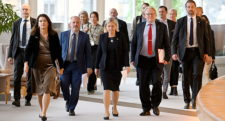 Fyra ministrar och flera andra personer går i en korridor.