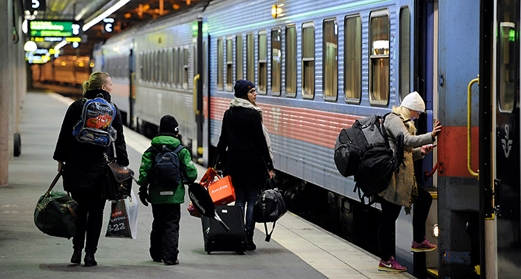 Några personer går på ett tåg på Stockholms centralstation.