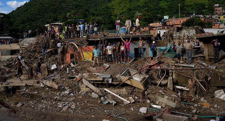 Människor utanför sina tasiga hus efter jordskred i Venezuela.
