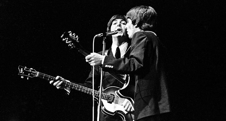 Två män vid en mikrofon som sjunger och spelar gitarr.