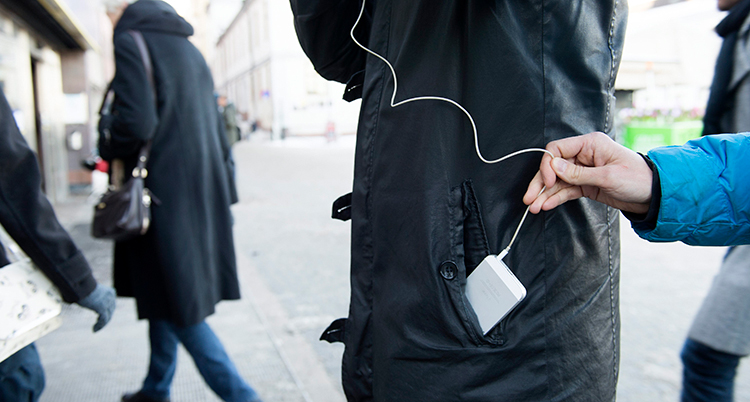 En hand drar i en sladd till en mobil som glider ur en ficka.