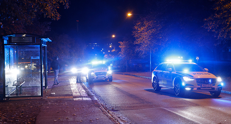 Polisbilar på en mörk gata.