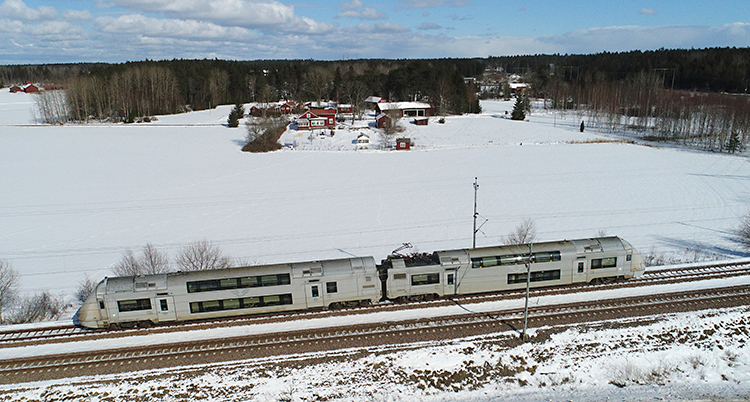 Ett tåg som kör genom ett vinterlandskap.