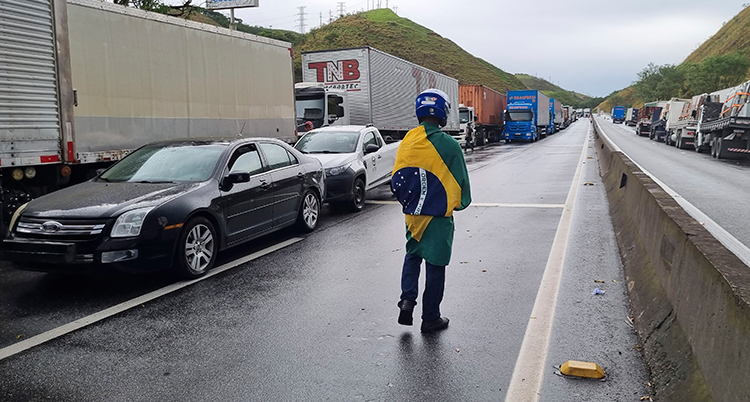 En man står på vägen. Han har Brasiliens flagga lindad runt sig.
