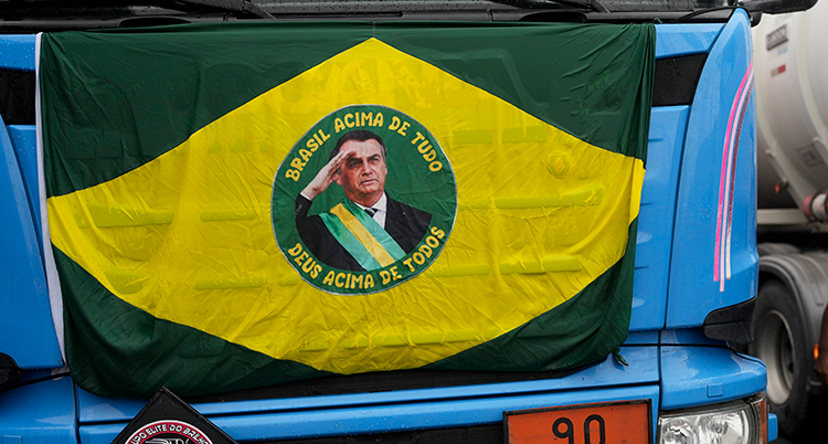 En flagga med en bild på Jair Bolsonaro och Brasiliens färger, gult och grönt, hänger på en lastbil.