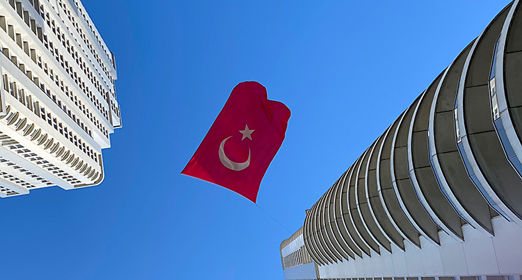 En turkisk flagga vajar mellan två höga hus.