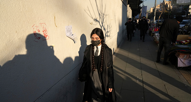 En kvinna med munskydd men utan slöja går på en gata.