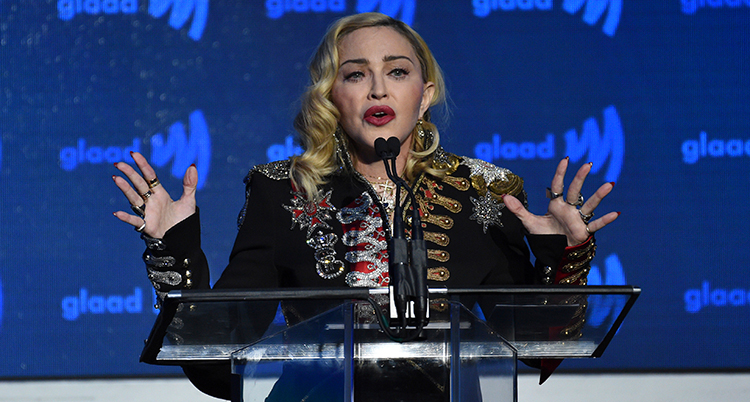 Madonna bakom en talarstol och en mikrofon.