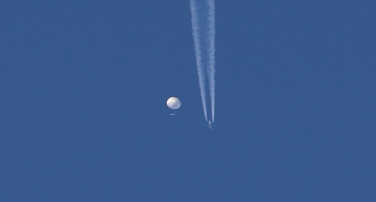 En ballong och ett flygplan syns långt borta, mot en blå himmel.