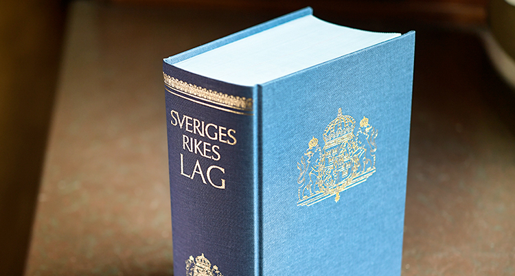 En tjock bok där det står Sveriges rikes lag på sidan.