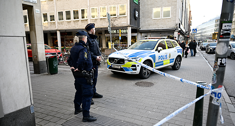 Två poliser står på en trottoar.