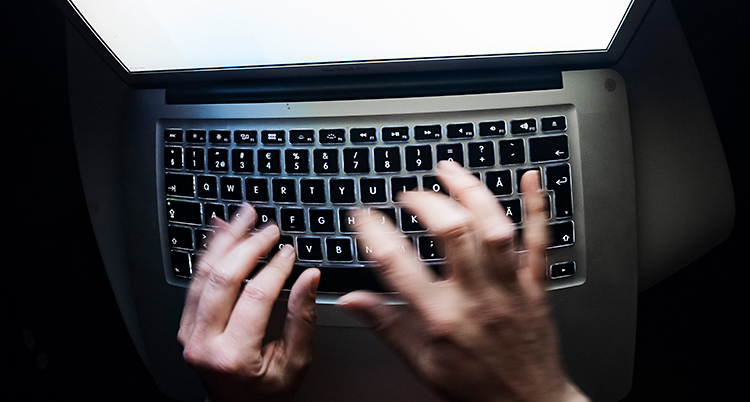 Två händer som skriver på tangentbordet på en dator.