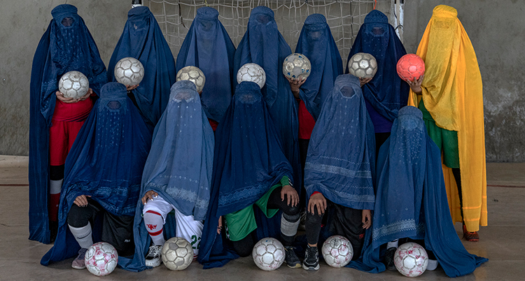 En grupp kvinnor med heltäckande kläder. De håller i varsin fotboll.