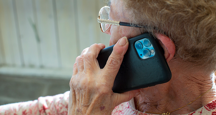 En gammal kvinna talar i en mobiltelefon.