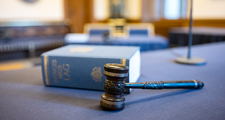 En lagbok och en domarklubba som ligger på ett bord i en domstol.