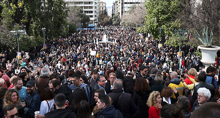 Många människor står på ett torg i staden Aten.