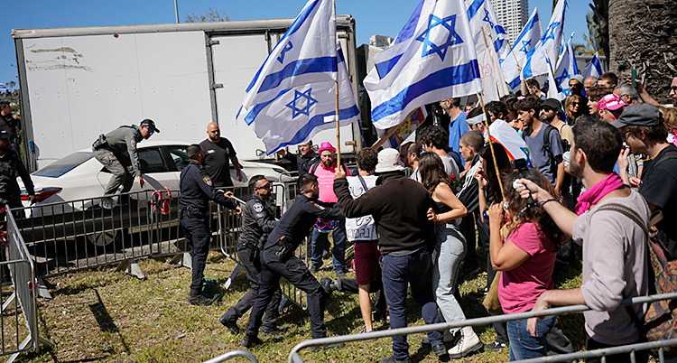 Flera människor är samlade ute på stan. De har israeliska flaggor. Poliser försöker stoppa dem.