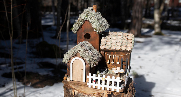 En fågelholk i form av små hus står på en stubbe.