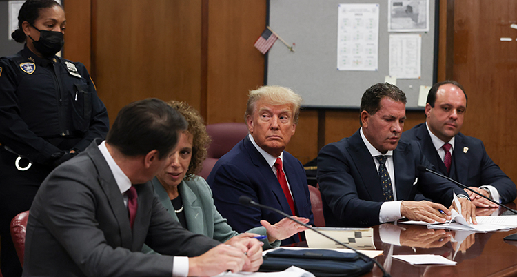 Donald Trump sitter vid ett bord. Fyra advokater sitter bredvid honom.