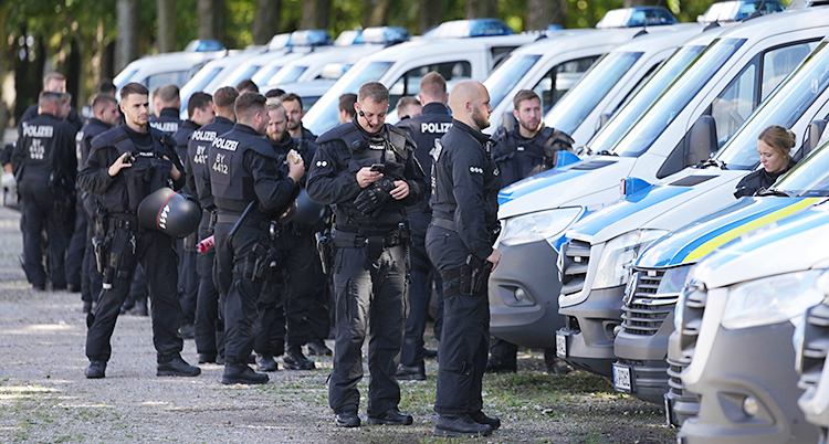 Flera tyska poliser står ute vid några polisbilar.