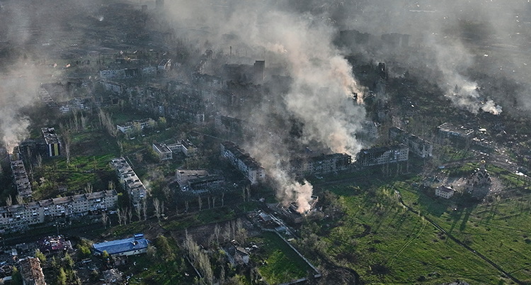 En flygbild över staden. Flera hus ser ut att brinna. Rök stiger från husen.