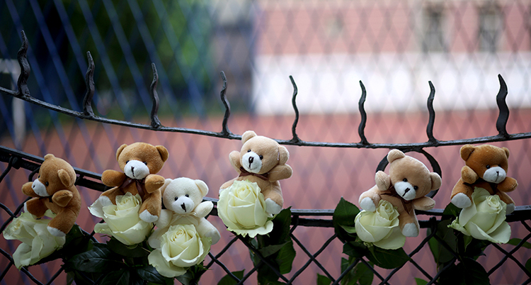 flera nallar och blommor hänger på ett staket.