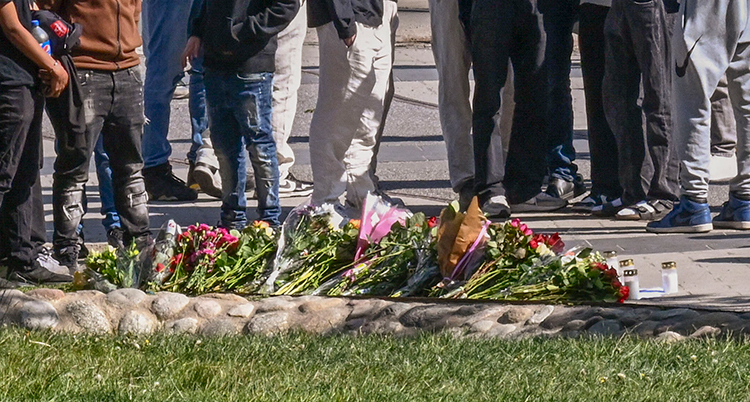 En hög med blommor och benen på människor som står bredvid.