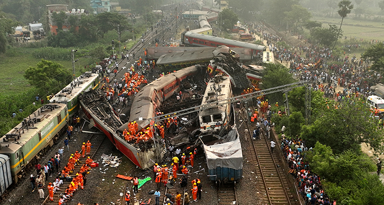 Arbetare i röda kläder syns bredvid flera tåg som krockat.