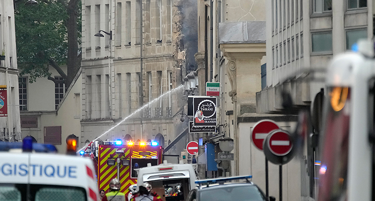 Brandmän på gatan sprutar vatten mot huset.