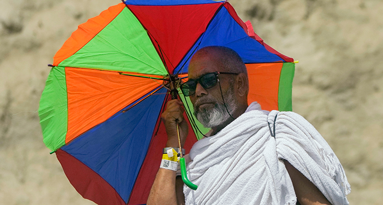 En man med solglasögon och ett färgglatt paraply.