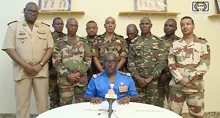 Nio militärer står uppställda. Framför dem sitter en tionde militär som pratar i en mikrofon.