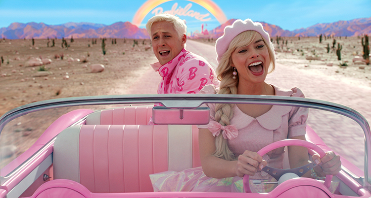 Barbie sitter bakom ratten i en rosa bil och kör genom en öken. Ken sitter i baksätet. Båda är glada.