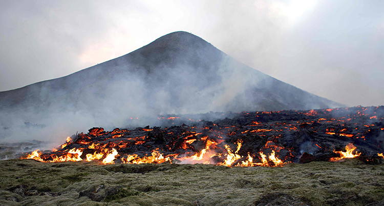 Glödande lava framför en vulkan.