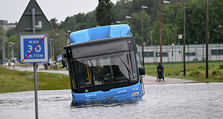 En buss står stilla i vatten. Det har kommit mycket vatten på vägen.