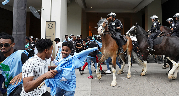 Poliser rider på hästar in bland människor.