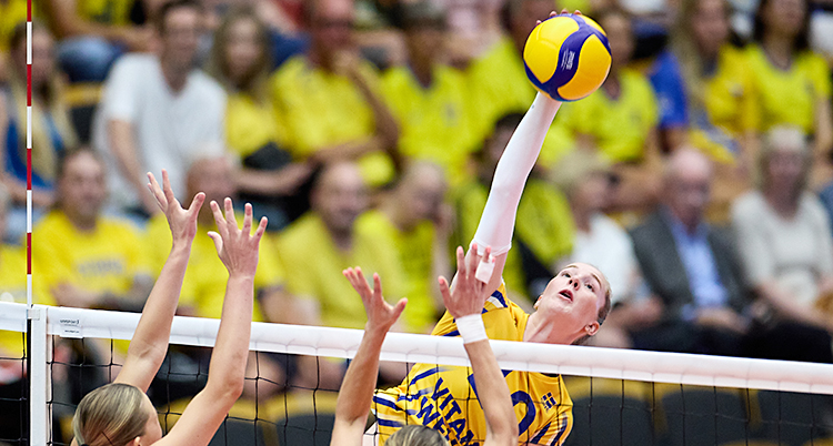 Från en match i volleyboll. Isabelle Haak är uppe i luften framme vid nätet. Hon slår till bollen med handen.