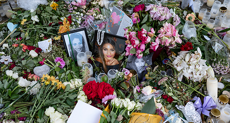 Folk har lagt blommor och ljus på marken. Det finns också bilder på Karolin Hakim där.