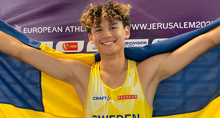 Glad idrottare håller upp svensk flagga med armarna.