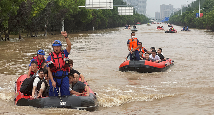 Människor i båtar på en översvämmad gata.