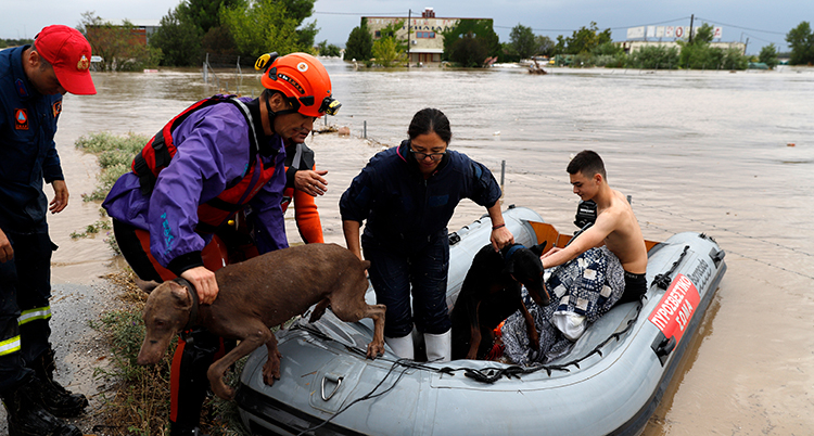 Räddningsarbetare hjälper folk fly med en gummitbåt.
