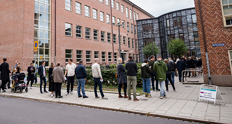 Flera personer står i kö utanför en skola i Malmö. De väntar på att få rösta i valet.